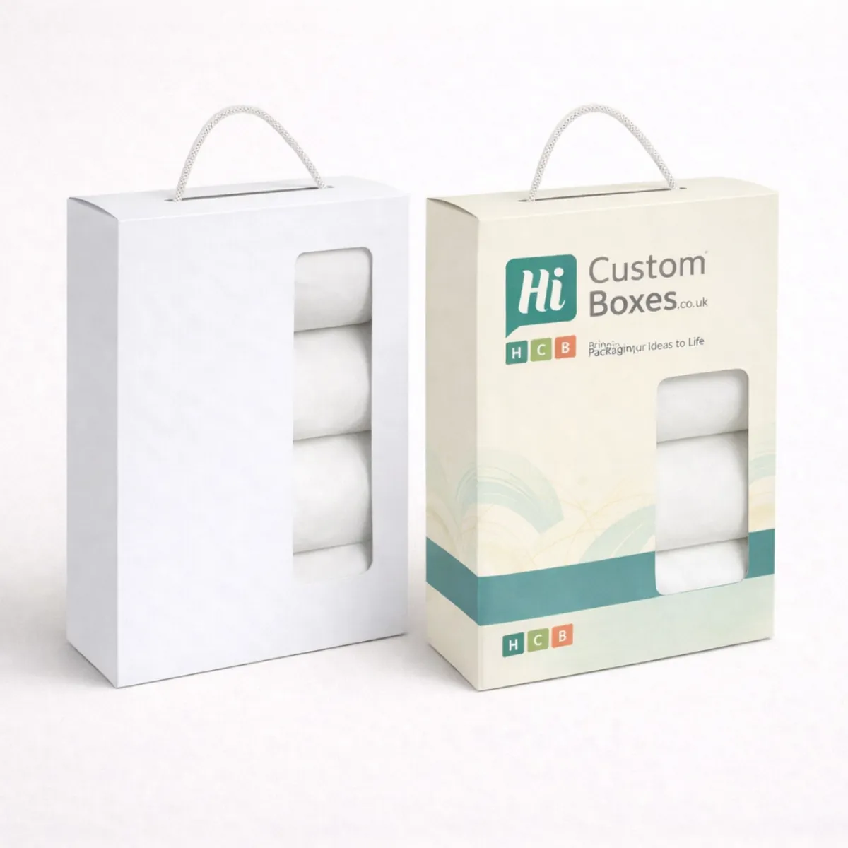 Two vertical retail boxes with rope handles and transparent windows showing folded white linen-